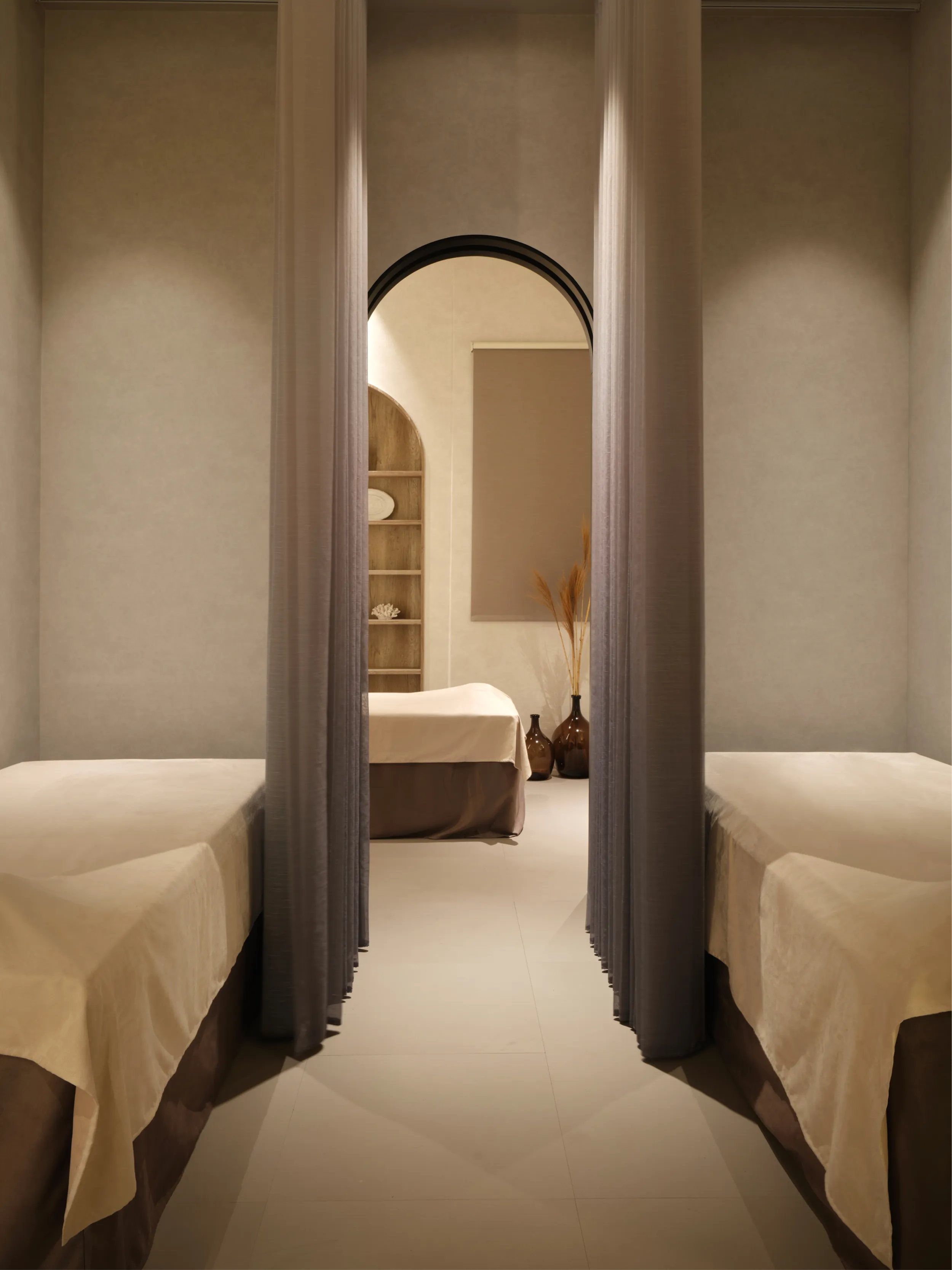 A SALIENT treatment room: two beds between soft curtains, with an arched doorway beyond